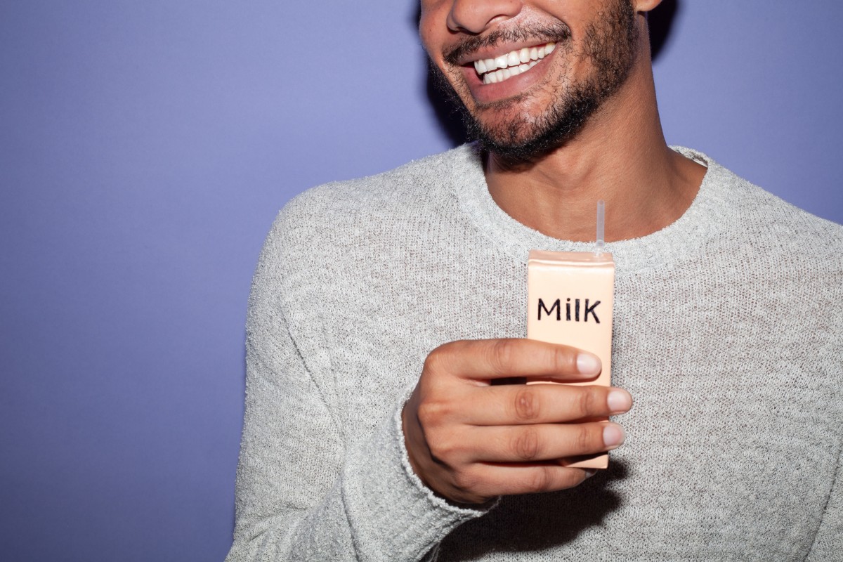 Man holding milk carton with purple background smiling
