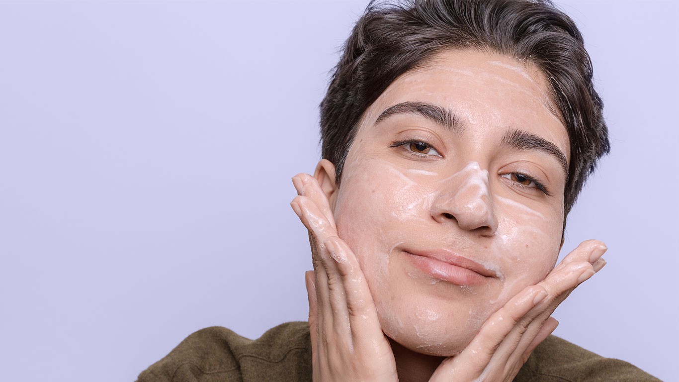 Person rubbing skincare cream on their face