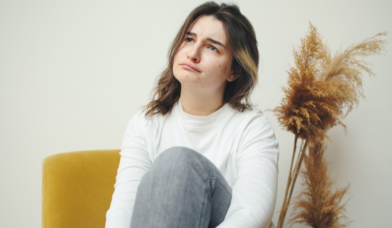 Woman sitting o a sofa with acne on her face