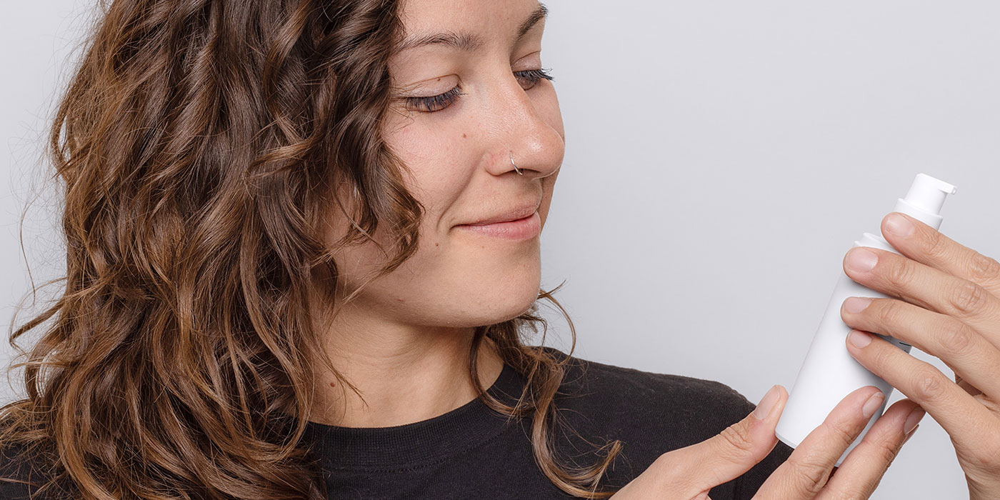 Woman Looking At Skincare Product - Acne Treatments