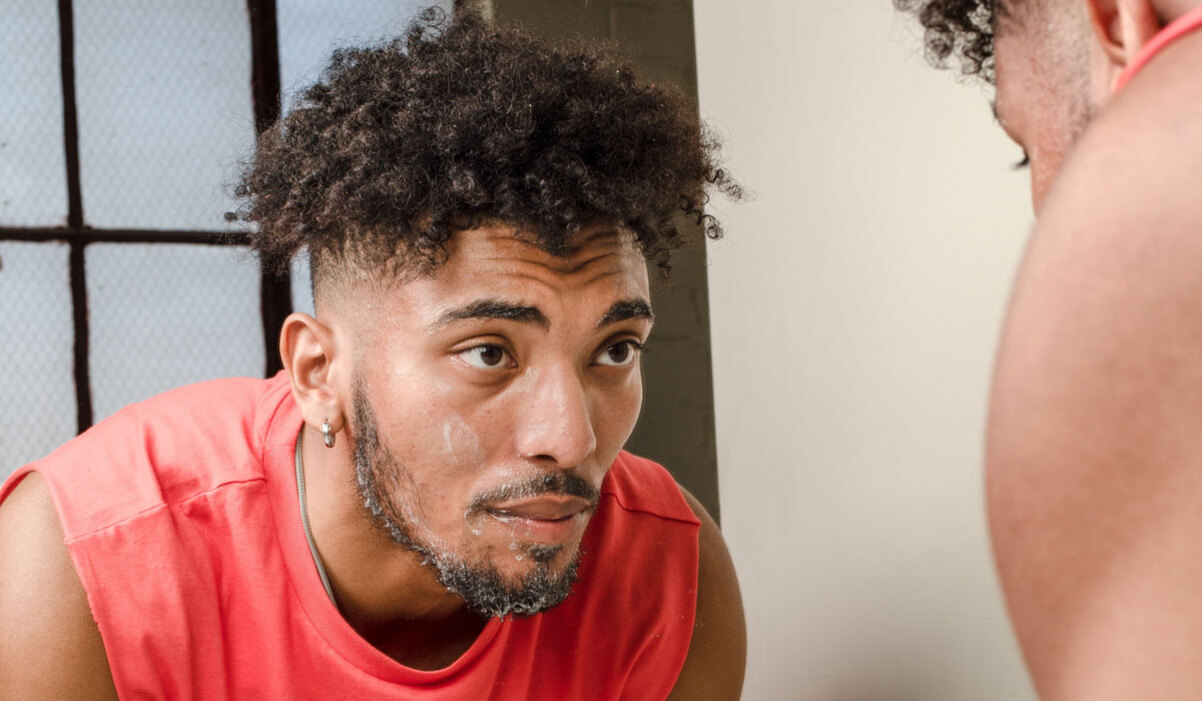 Man cleansing face in front of mirror