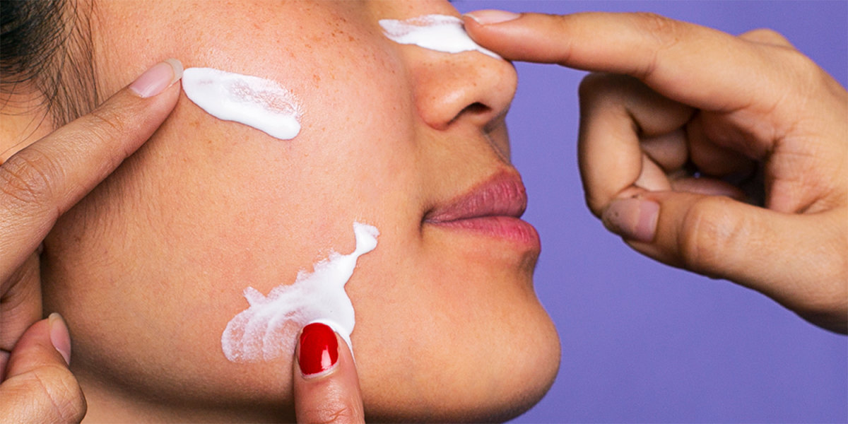 Multiple people putting skincare cream on person's face