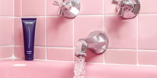 Curology cleanser on pink bathtub with running water and pink tile background
