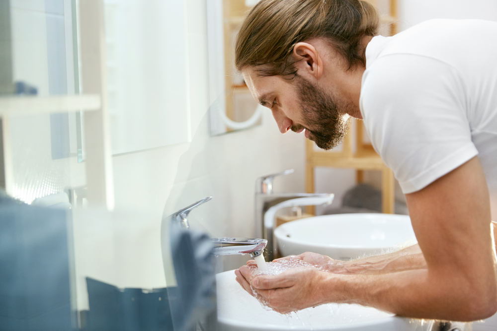 man washing his face in the bathroom