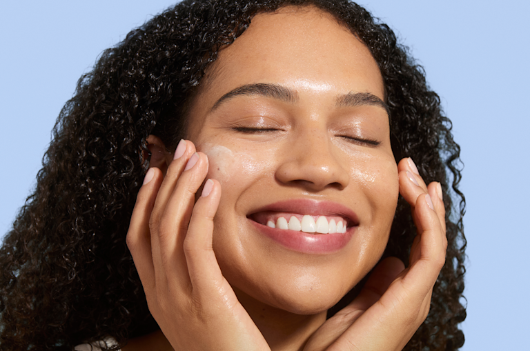 Person applying a lightweight Curology skincare product to their face, illustrating a daytime routine designed to prep skin and support acne care.