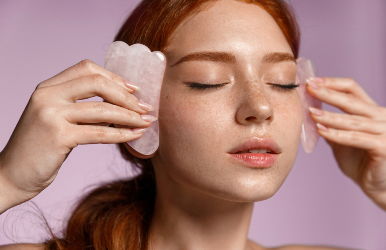 Redhead woman doing gua sha on her face
