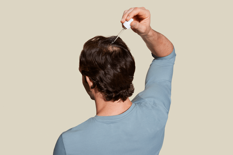 Brunette male applying hair treatment