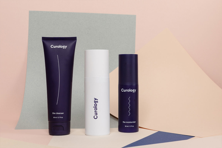 Curology set with cleanser, Curology bottle, and moisturizer against abstract shapes and pale neutral background