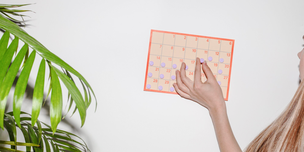 Person placing pill on calendar