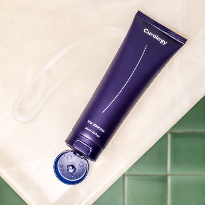 Curology cleanser bottle open above green tile floors