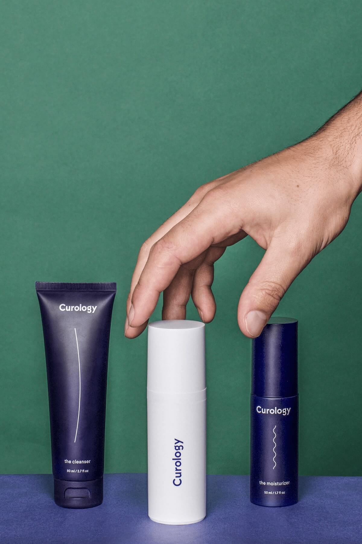 Hand reaching for curology bottle with other curology bottles nearby