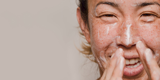 Close up of woman with cream on her face, holding hands near face