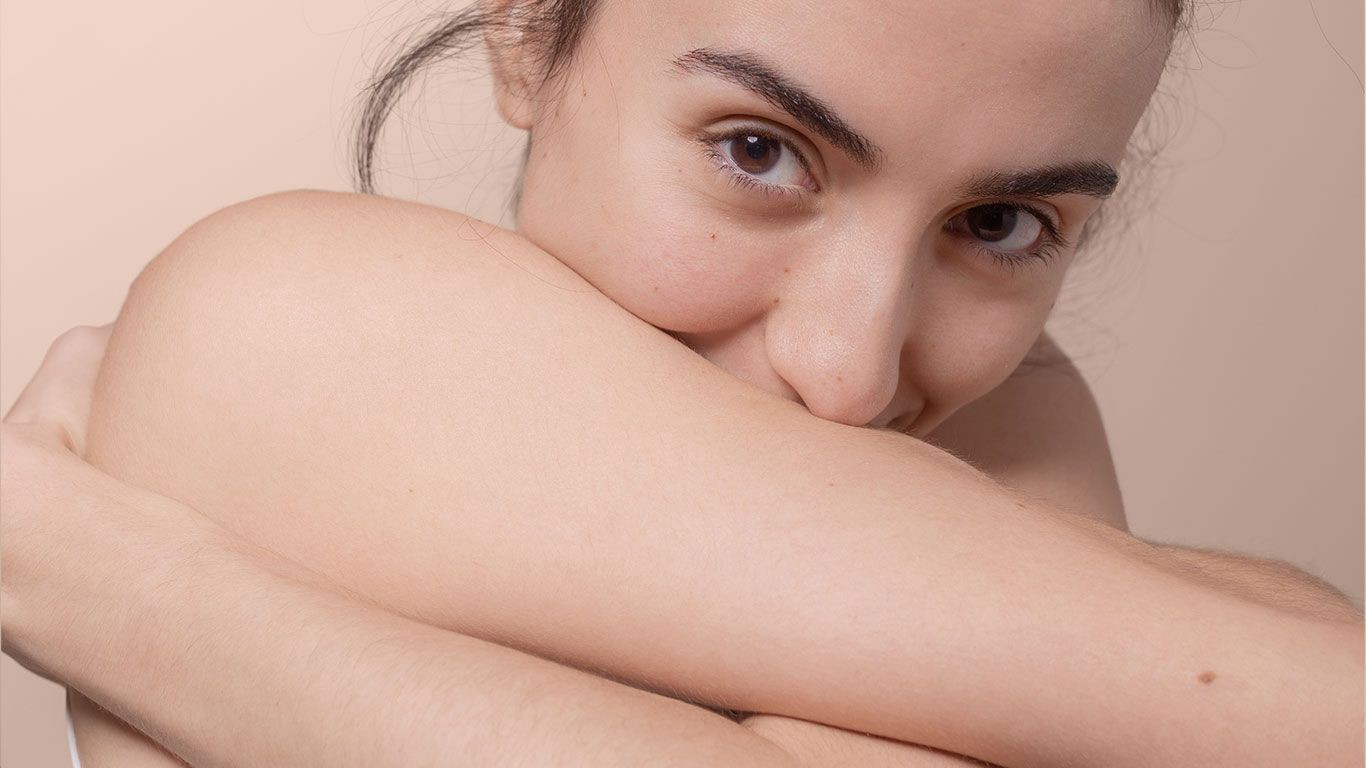 Woman wrapping arms around herself body acne