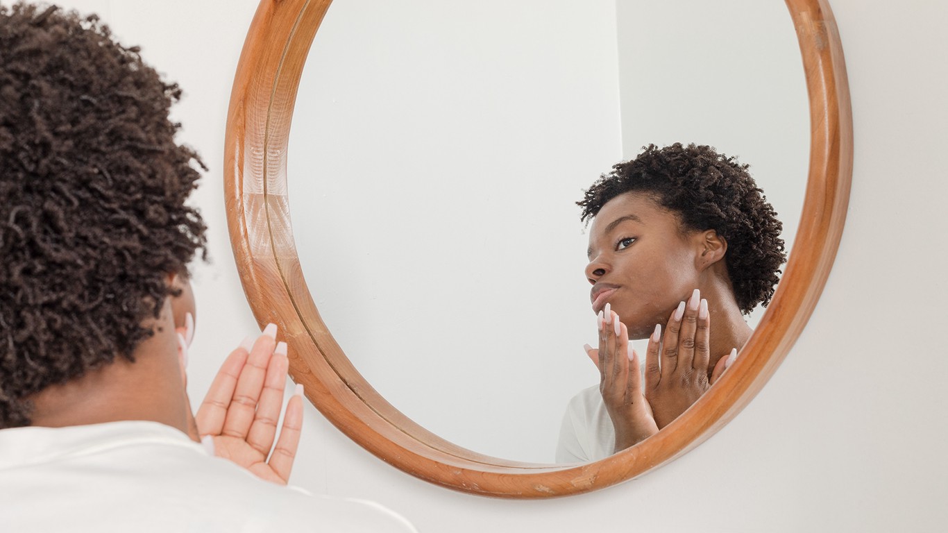Woman looking into mirror and using moisturizer