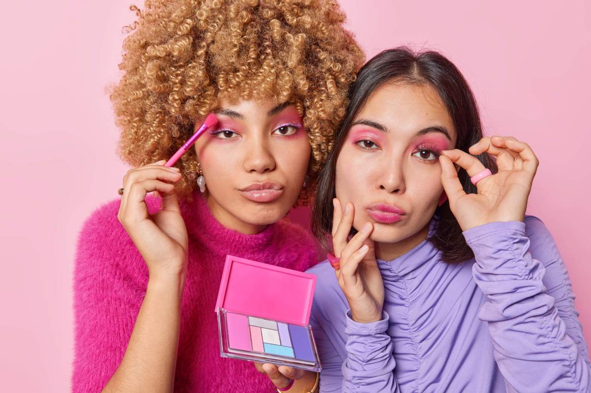 two young women sharing makeup products