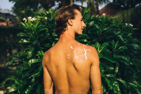 shirtless man with sunscreen shaped as the sun on his back