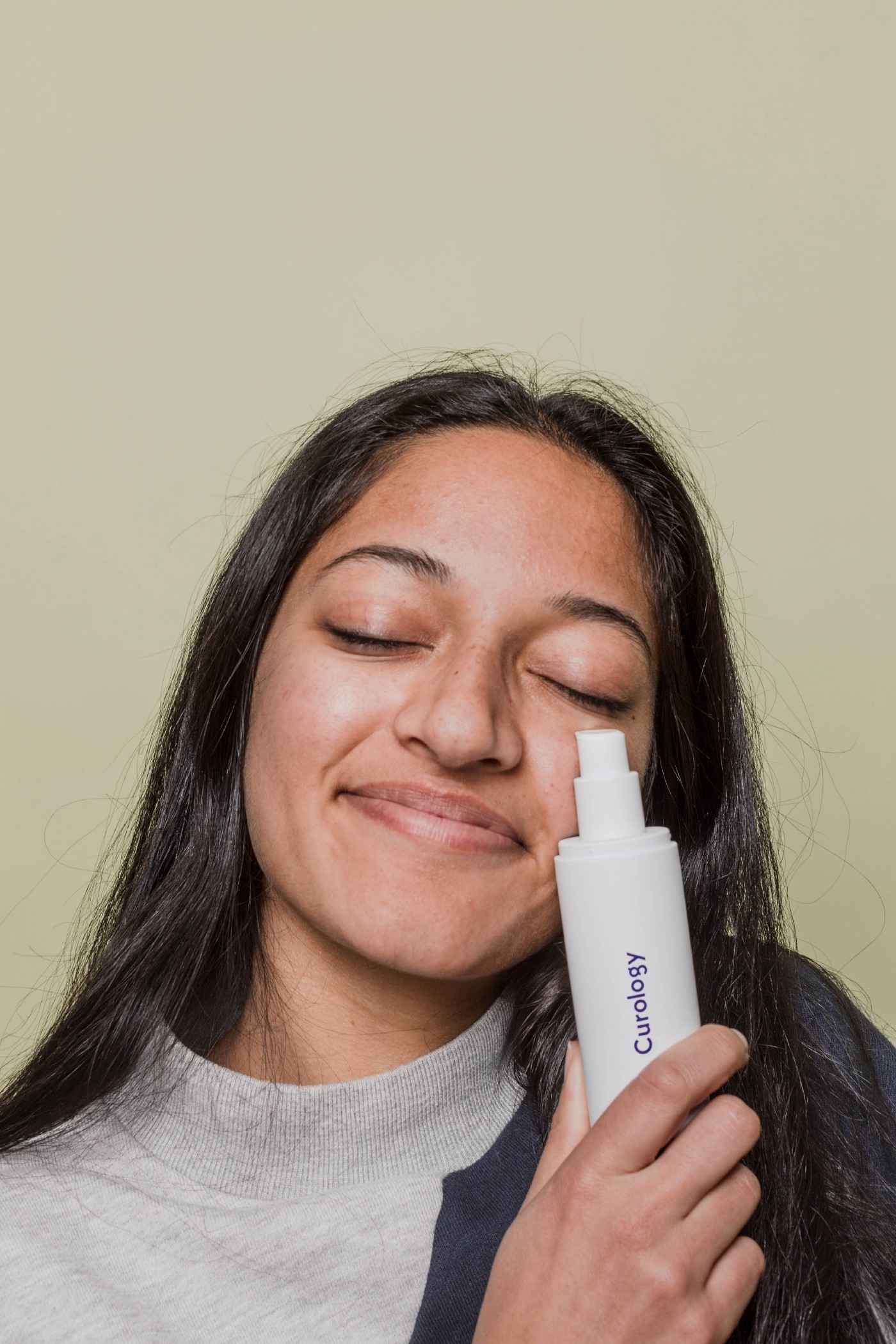 Woman holding curology custom bottle against her face and smiling