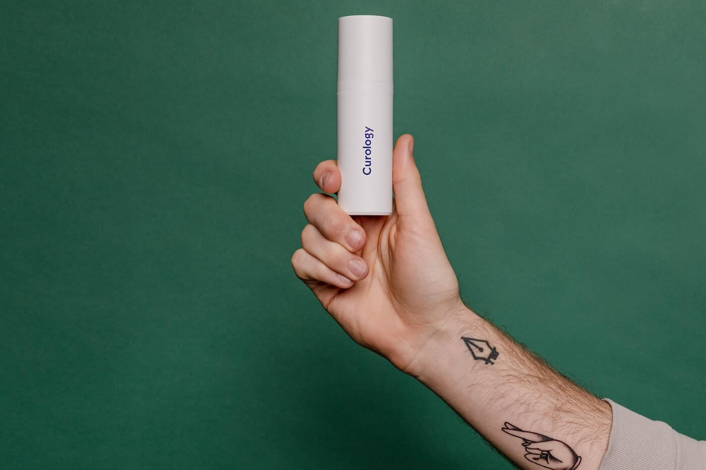 Arm with tattoos holding curology bottle