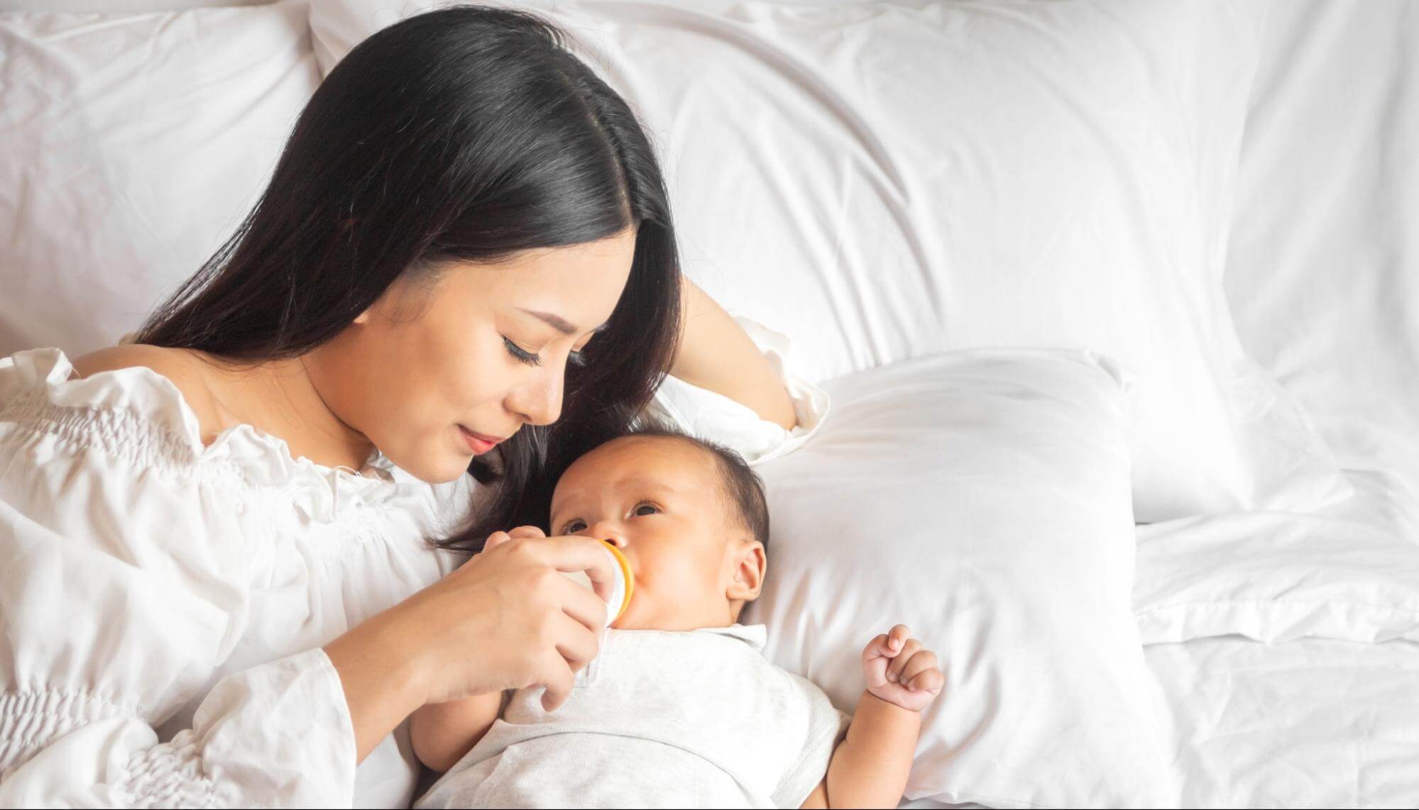 Woman Lying with Baby Holding Bottle