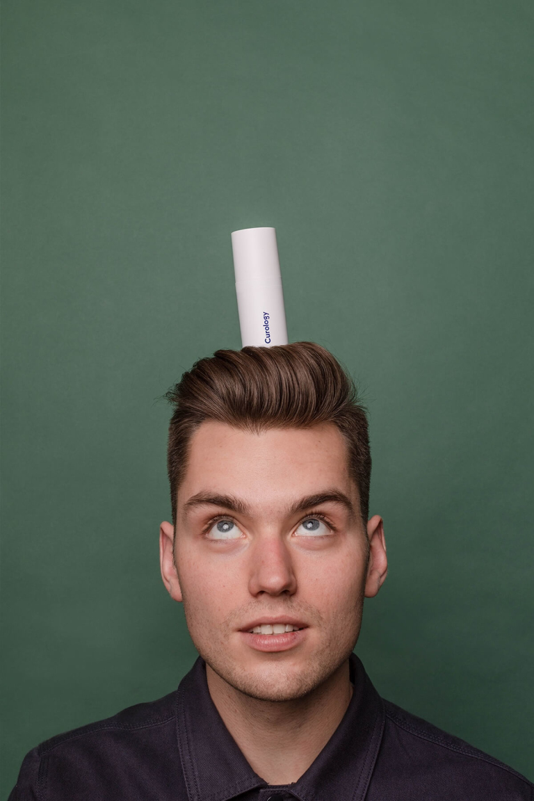 Man looking up with curology bottle his head