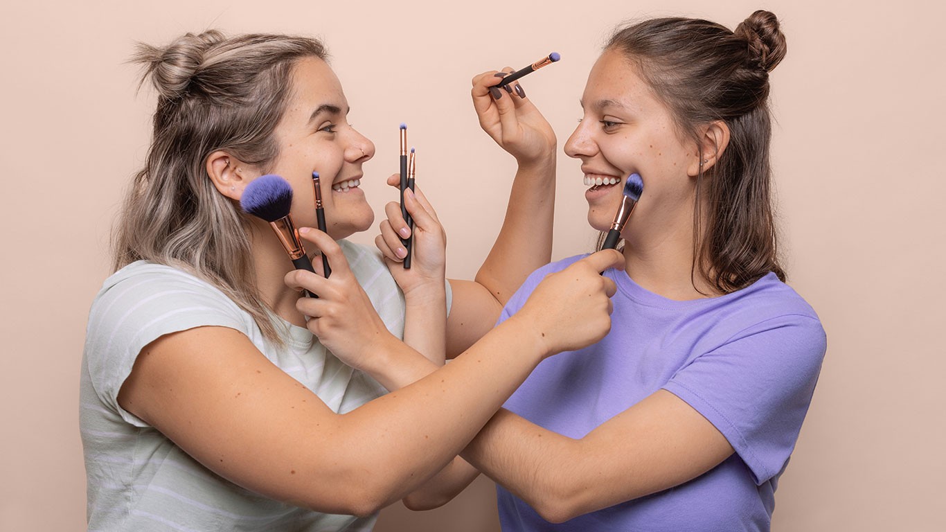 Two women with pressing brushes into their faces