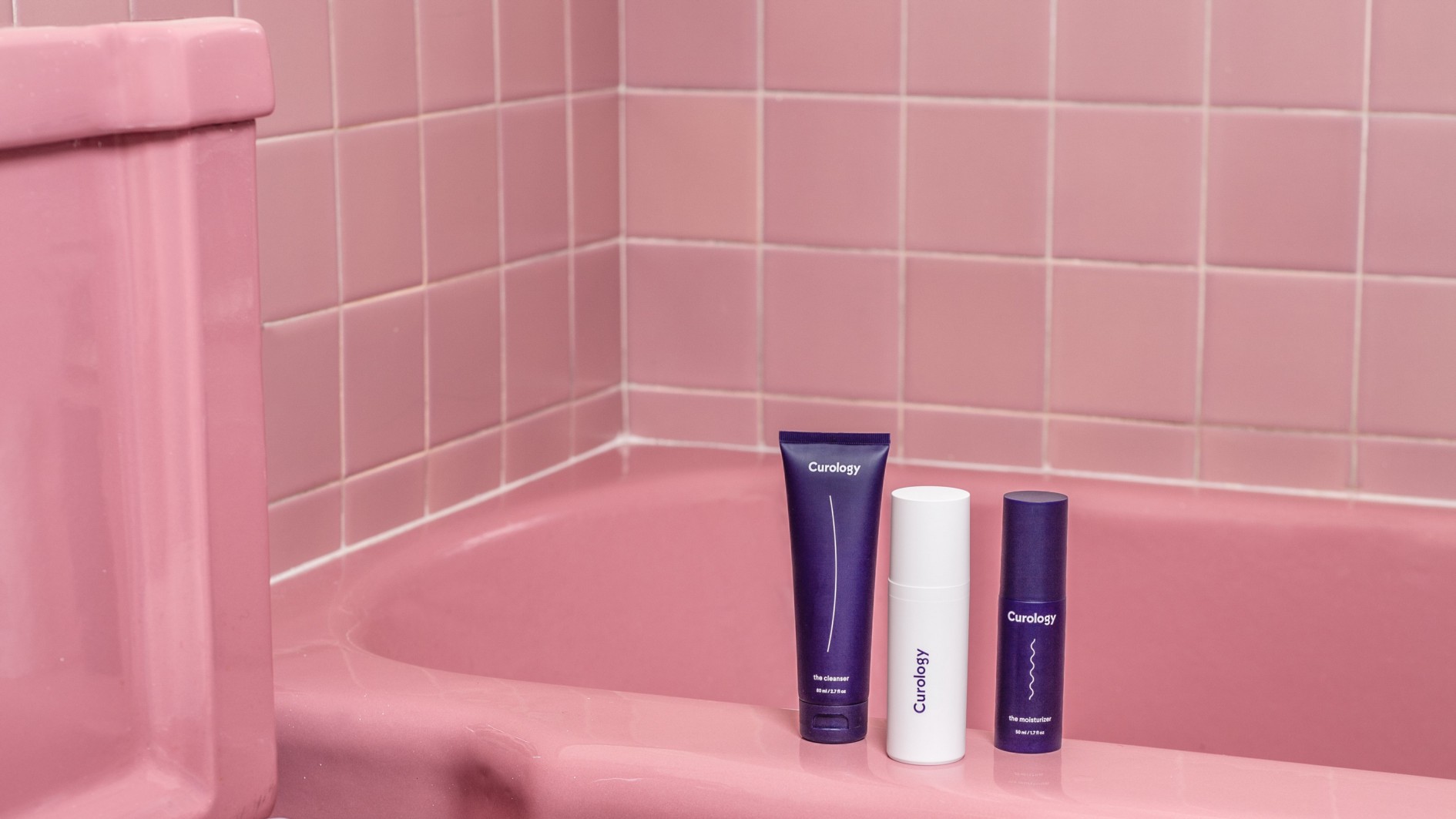 Curology bottles next to pink tiled bathtub in bathroom