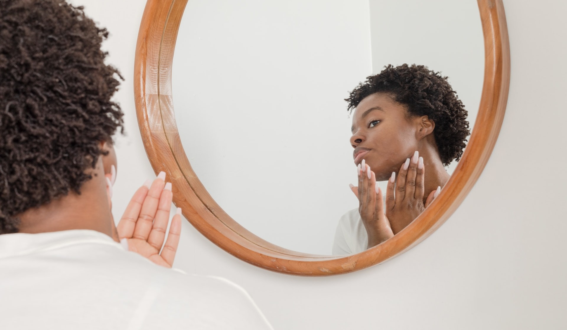 woman looking at skin in a mirror