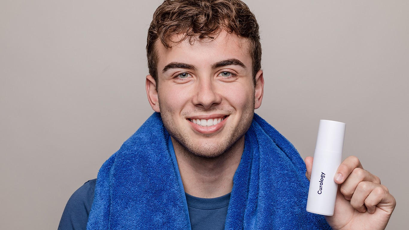 Man holding curology bottle with blue towel on his neck