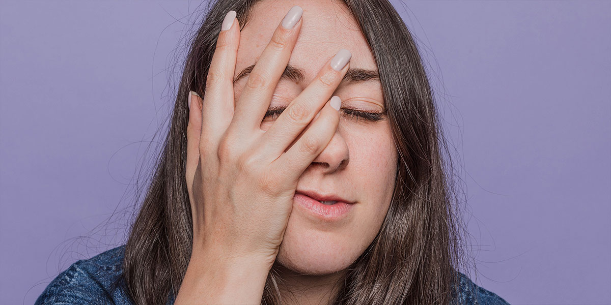 A woman's hand rests on her face, as if she's just smacked herself out of frustration. 