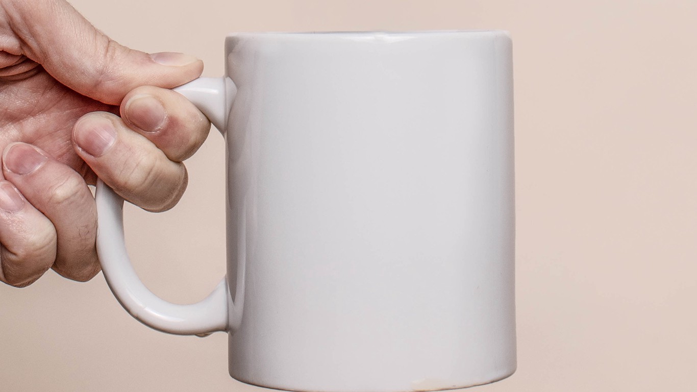 Hand holding white mug with neutral background