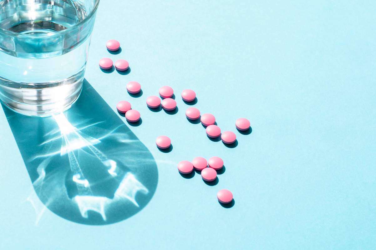 pink vitamins and glass of water 