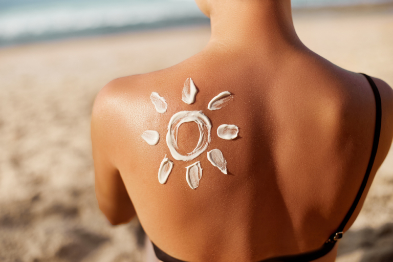 Woman Applying Sun Cream on Tanned Shoulder In Form Of The Sun.