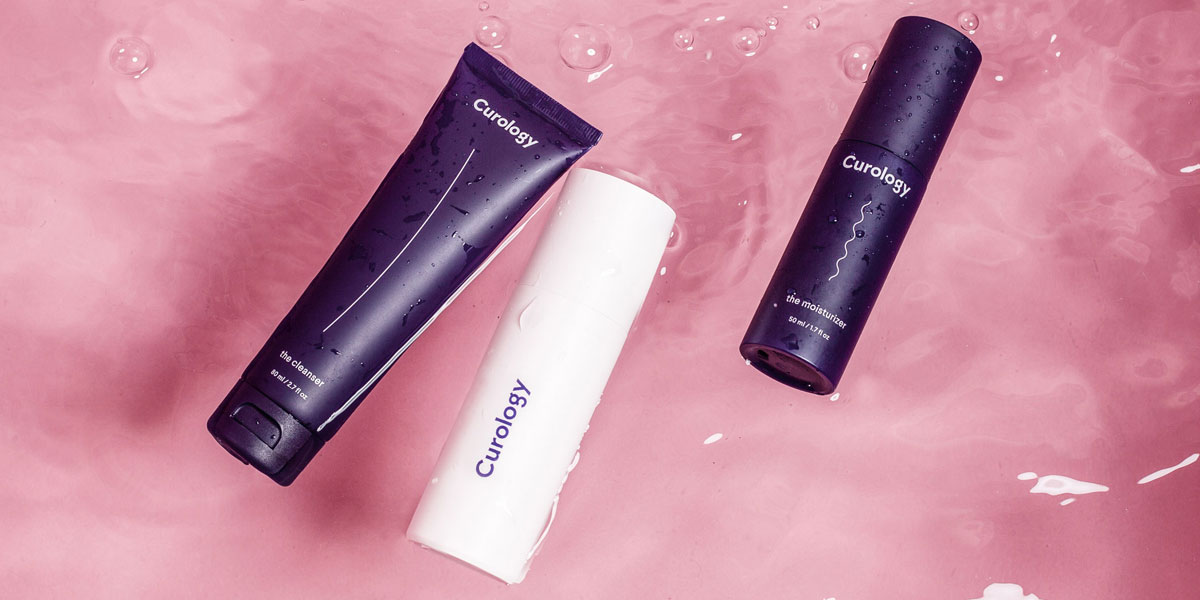 The Curology set floating in a pink bathtub filled with water