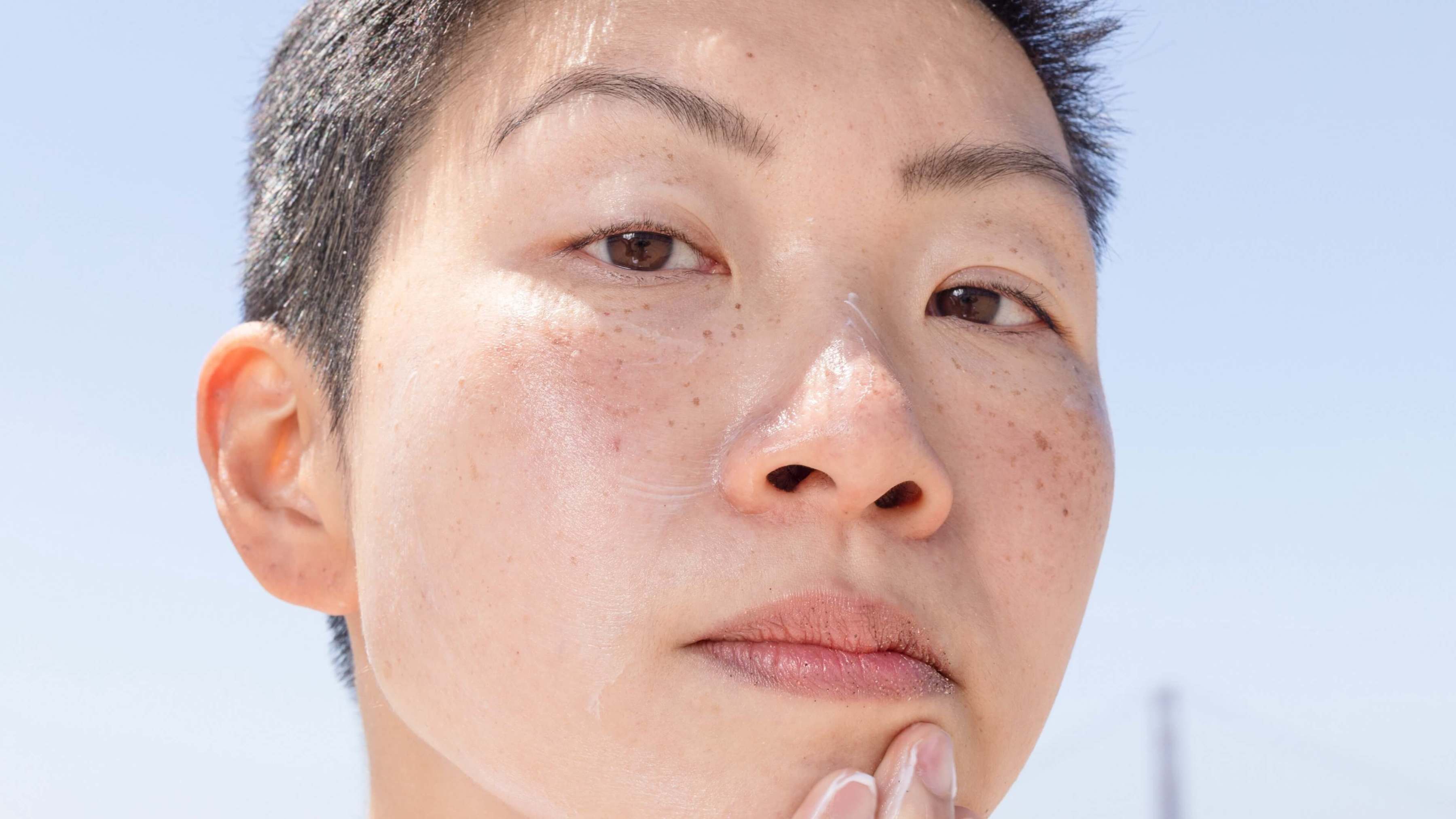 Person putting on sun screen and looking at the camera