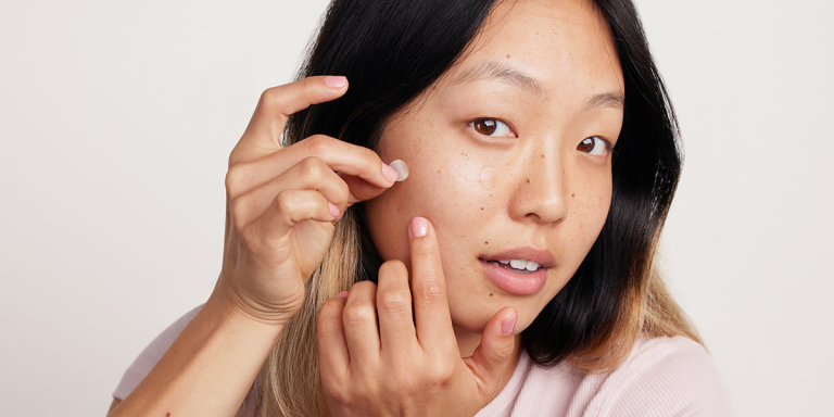 Woman applying Curology Emergency Spot Patch To Pimple