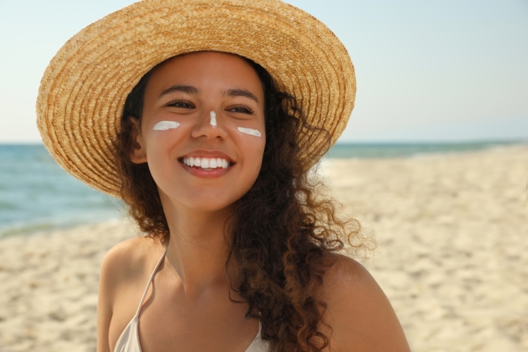 woman on beach using sunscreen