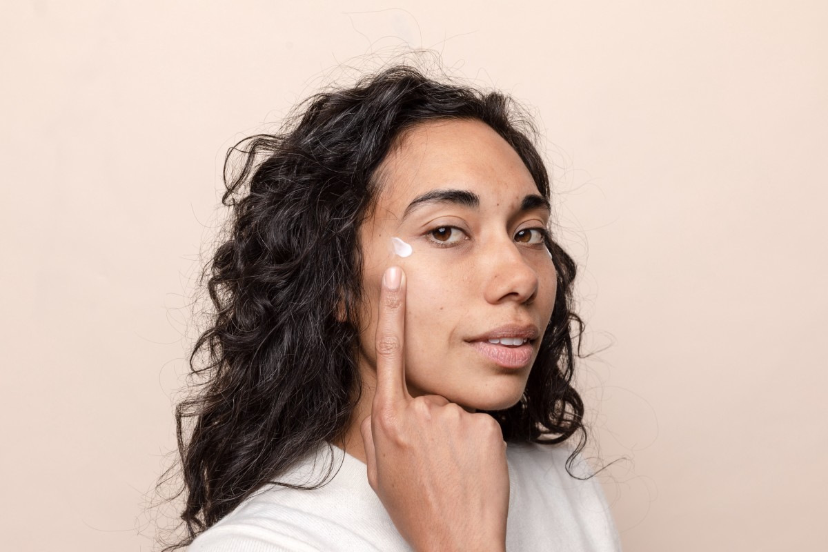 Woman pointing at skincare cream near her eye