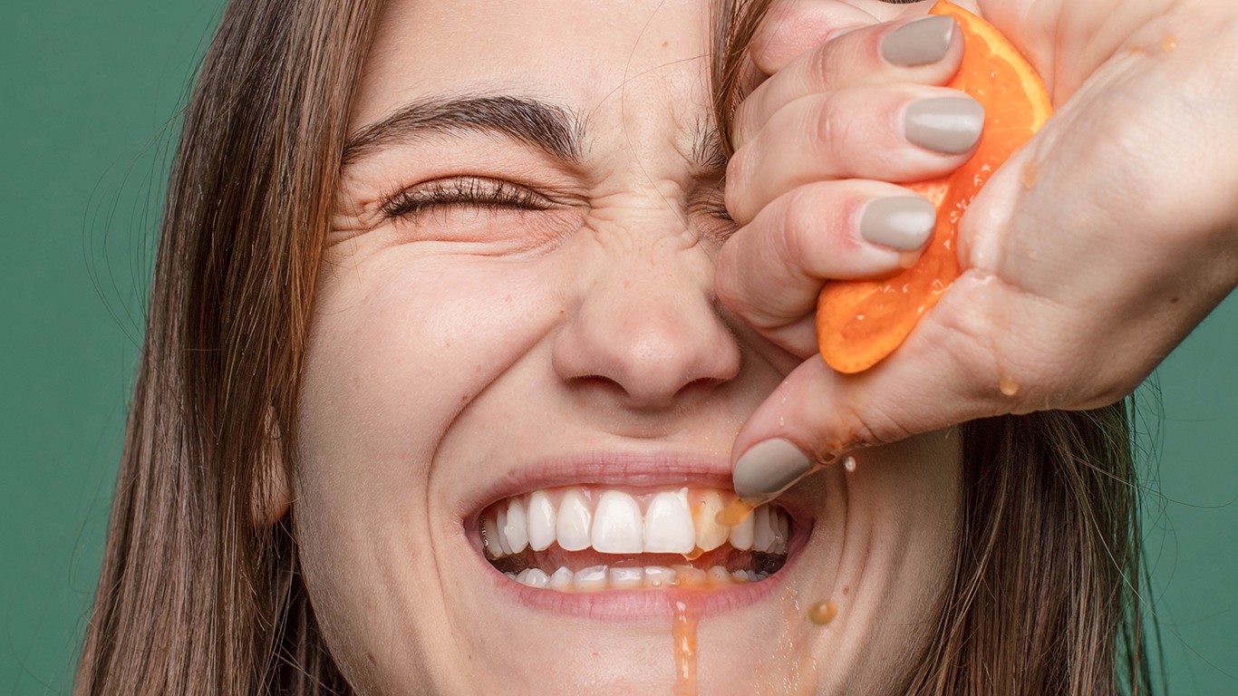 Woman squeezing orange with green background