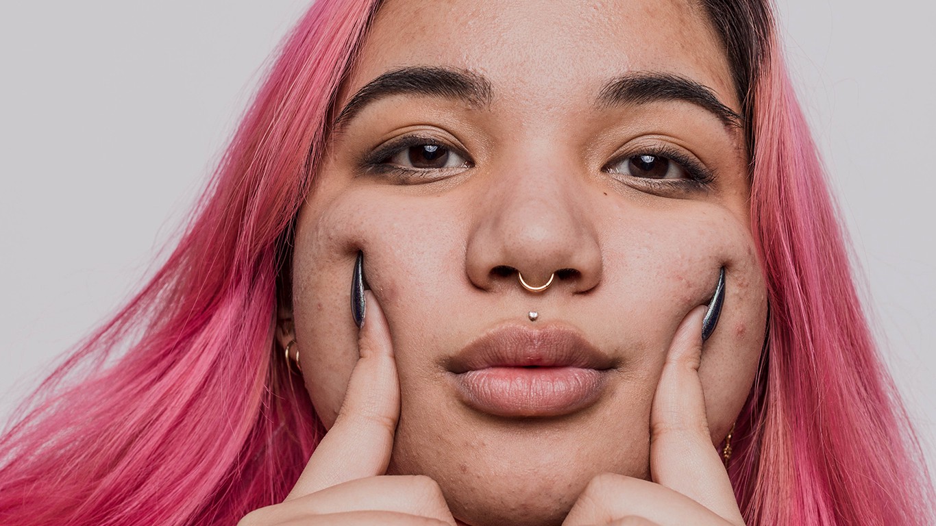 Woman with pink hair pressing fingers into her cheeks
