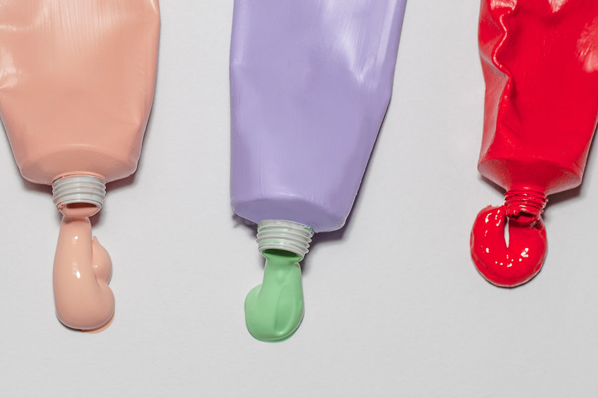 Close-up on tubes of paint that look as though pigment has just been squeezed out 