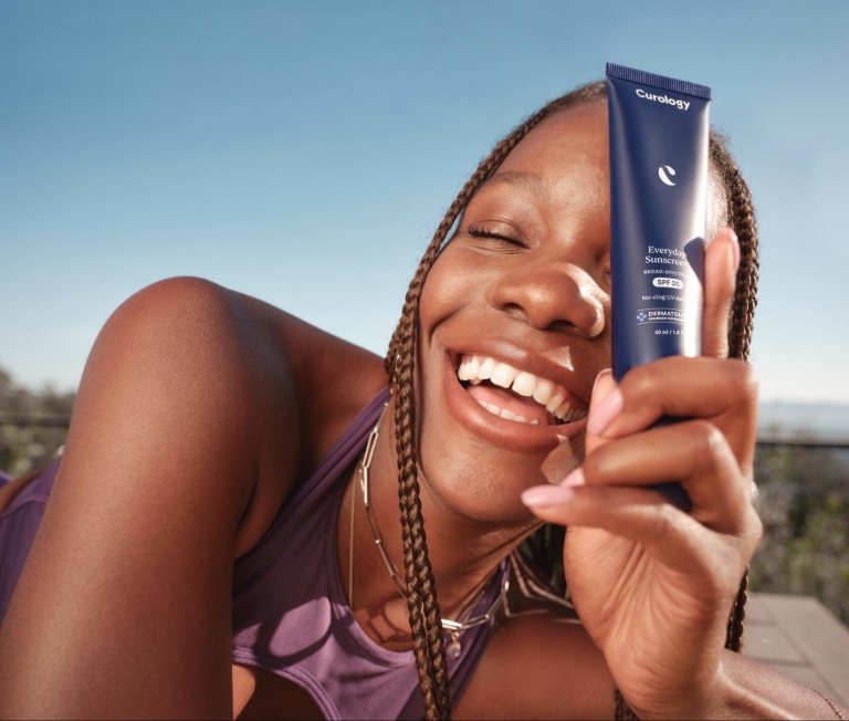 Happy Woman Holding Curology's Everyday Sunscreen