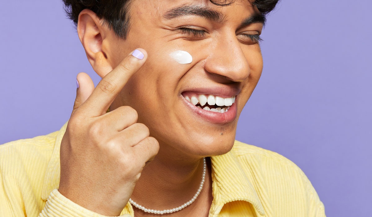 Young-man-applying-skincare-product-to-cheek