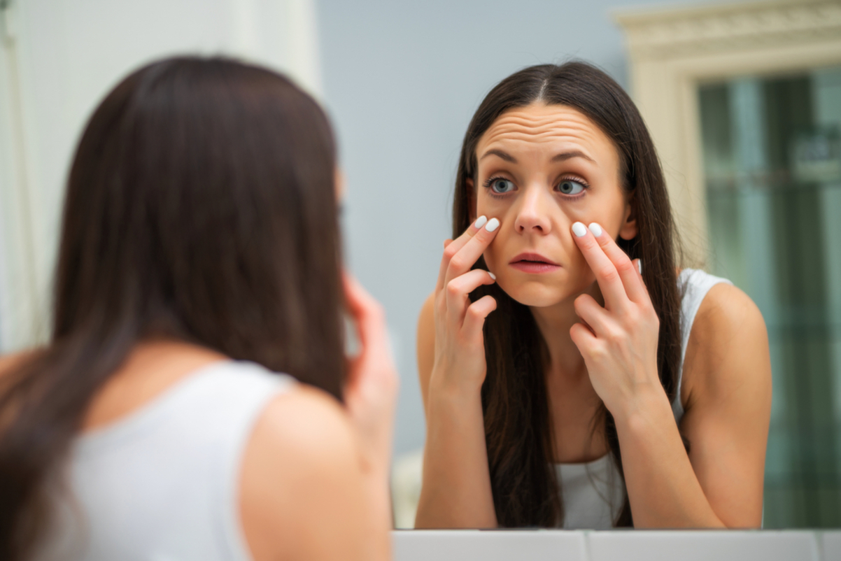 Tired woman looking at her eye bags