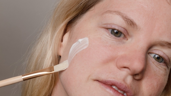 Woman using brush to add skincare cream