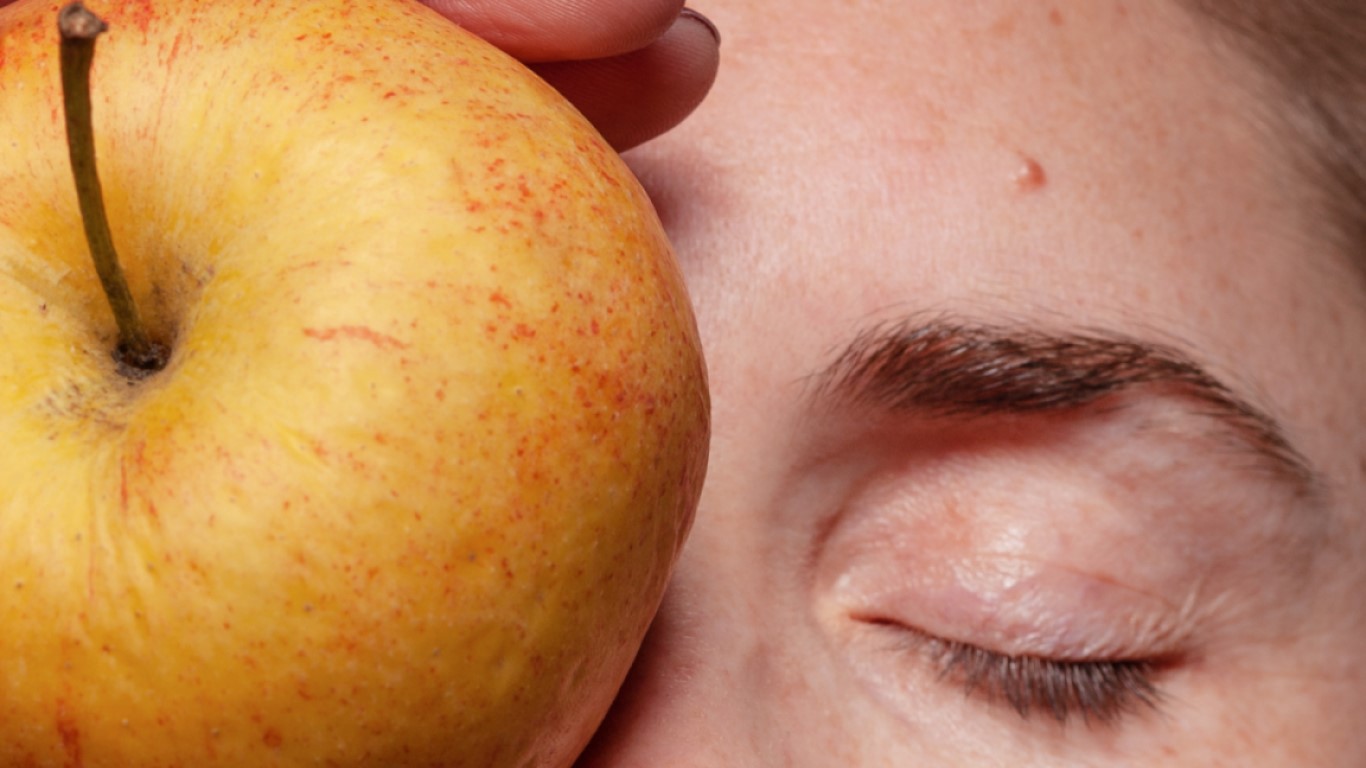 Closeup of person with apple on their face