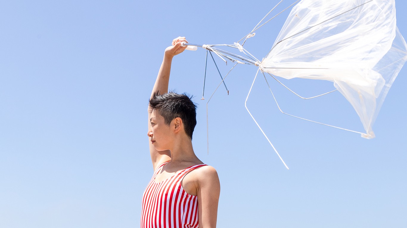Person holding broken umbrella with red and white striped top