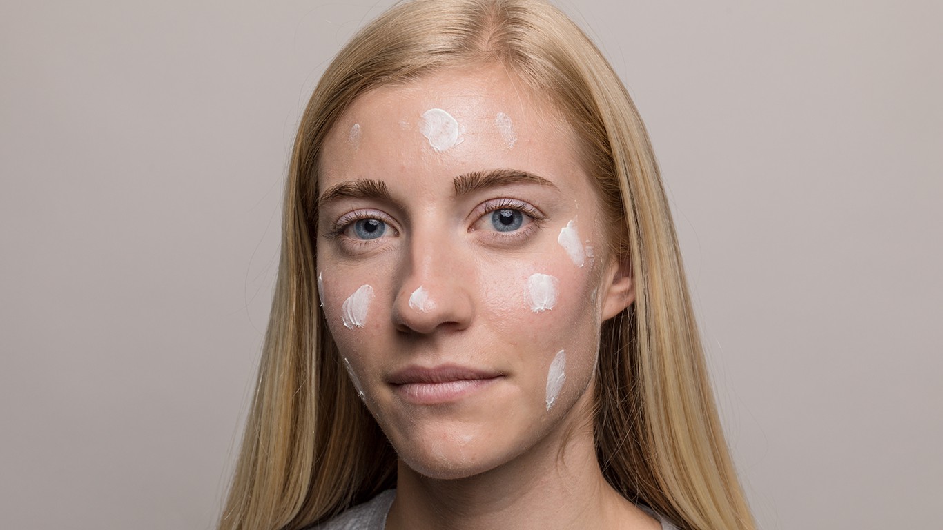 Closeup of woman with skincare cream in spots around face