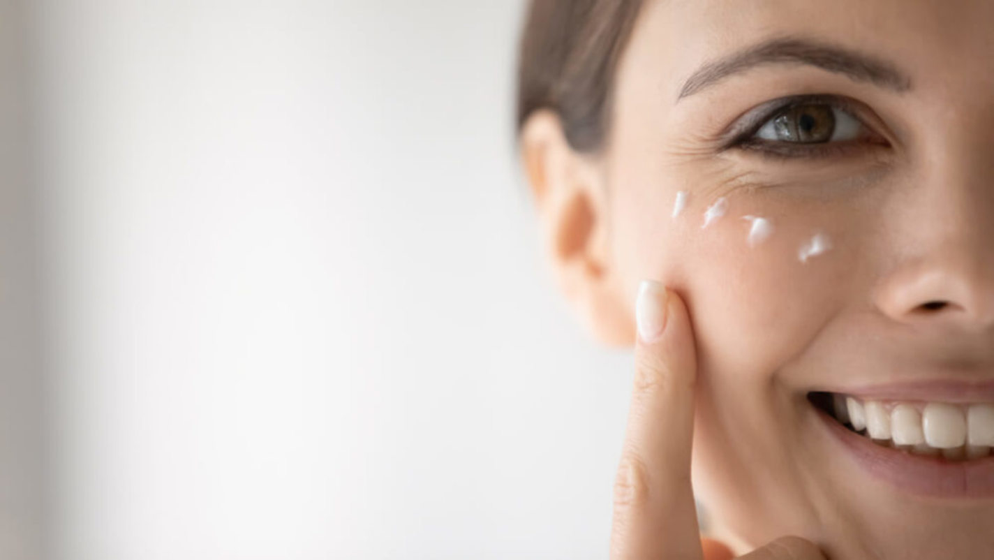 Woman Dotting White Cream on her Cheeks with a Fingertip