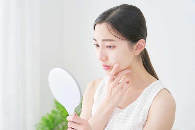 woman looking at her skin on a little mirror