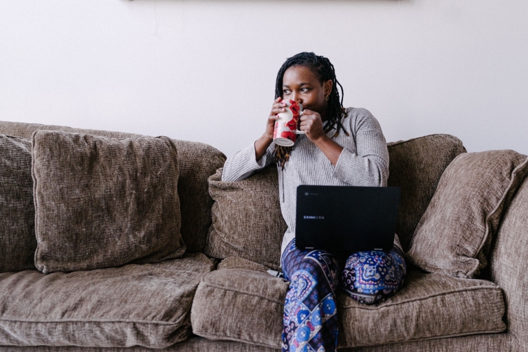 Woman drinking out of mug with laptop